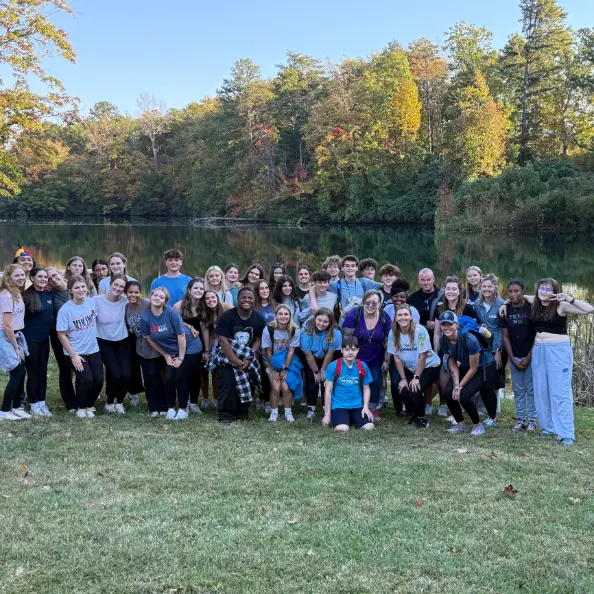 The whole Teen Retreat group, teens and staff together, posed on the grass in front of the lake in autumn