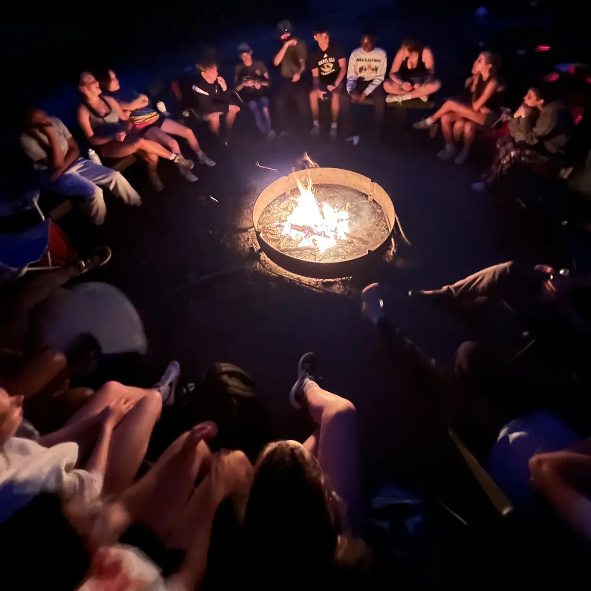 Campers bonding around the firepit at night