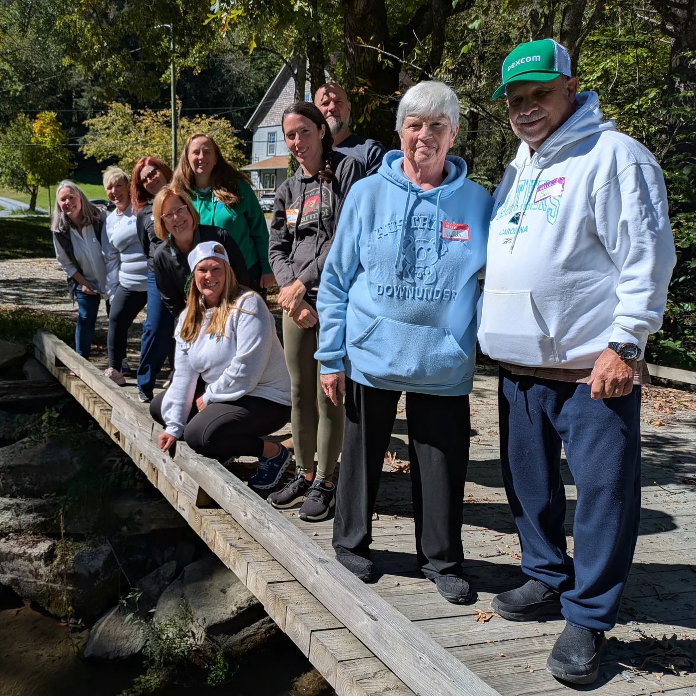 Caregivers and volunteers standing together on a wooden footbridge at a Camp to Community day