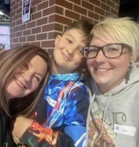 A camper and two caregivers smiling together at a Camp to Community event