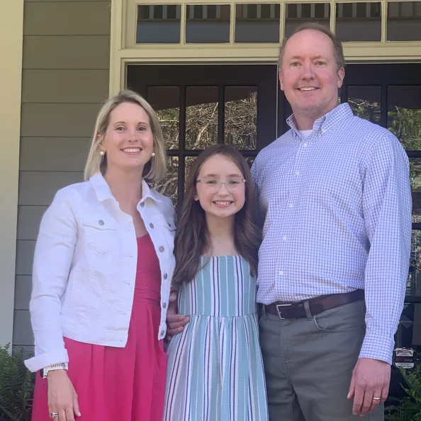 A mother, father and daughter standing together on their front porch before a Party with a Purpose