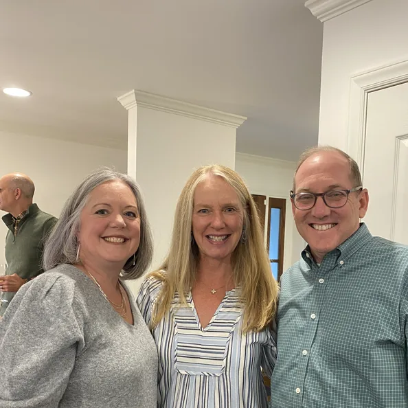 Three guests smiling together in a kitchen at a Party with a Purpose gathering