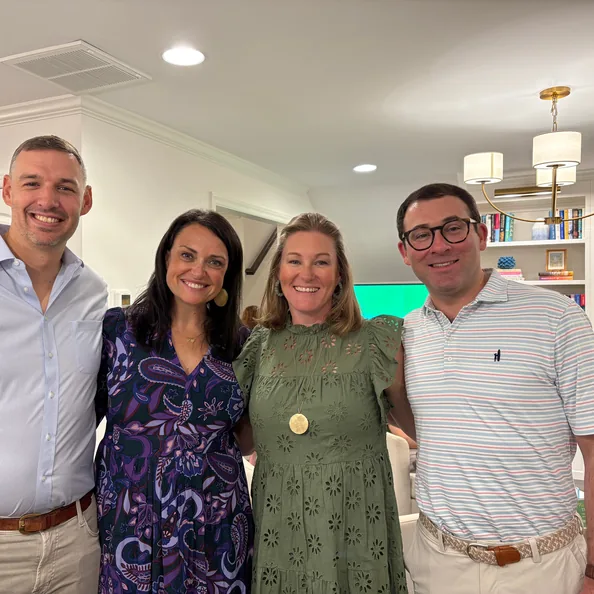Four guests standing arm in arm in a living room at a Party with a Purpose