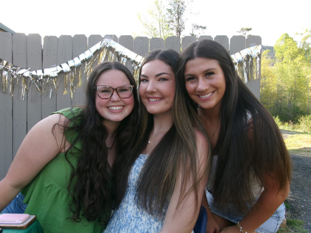Three DFC volunteers smiling together at an outdoor gathering