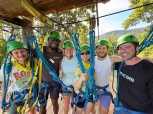 Bobby and fellow counselors in green helmets and harnesses on the ropes course platform