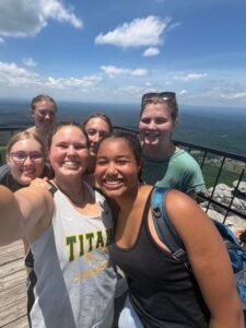 Kennedy taking a selfie with four camp friends at a sunny mountain overlook
